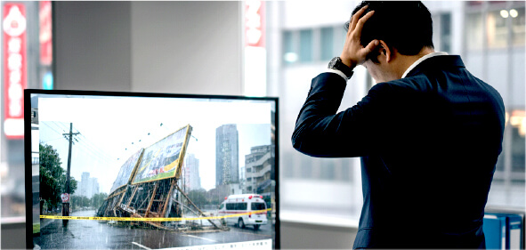 古くなった看板とニュース画面を見て不安そうな表情のイメージ